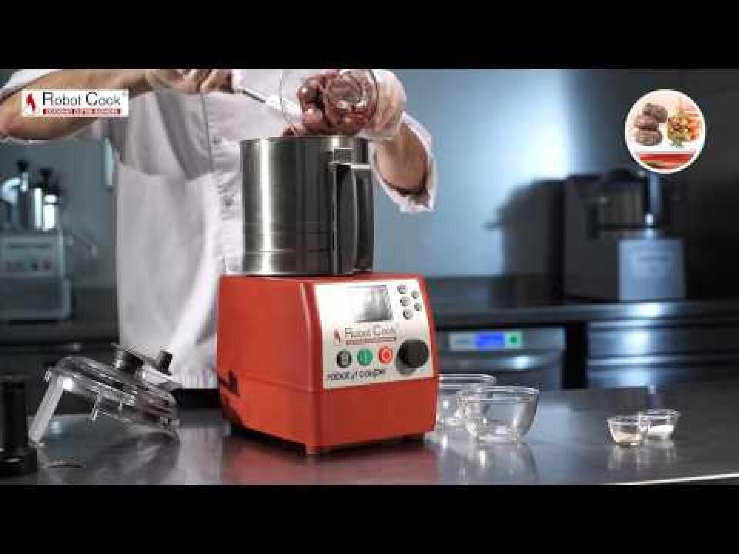 Une personne met des ingrédients dans un robot de cuisine Robot Cook rouge posé sur un plan de travail en acier inoxydable dans une grande cuisine. Le couvercle du robot de cuisine est retiré et quelques petits bols en verre sont placés à côté.