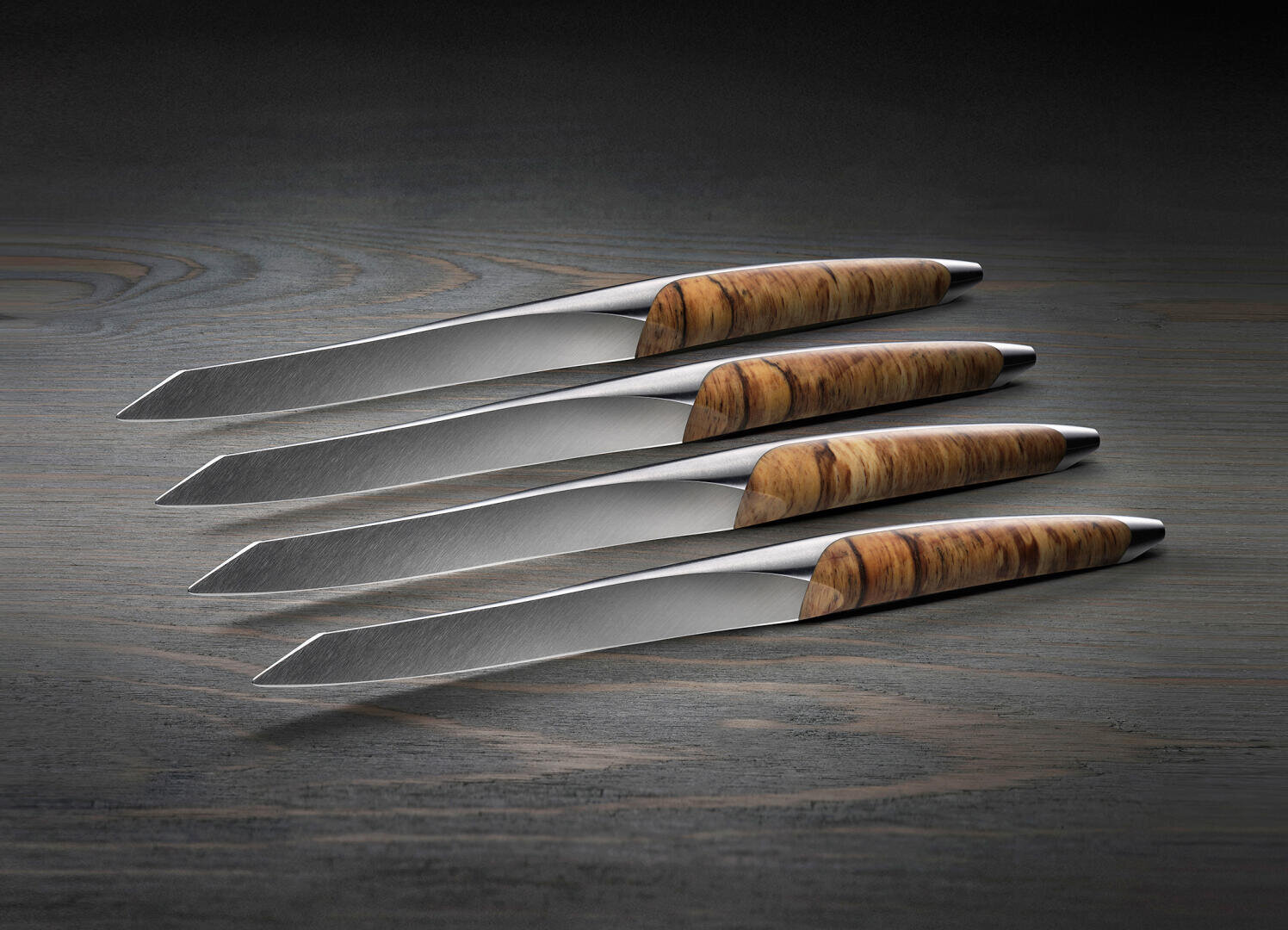 Vier moderne Messer mit glatten, silbernen Klingen und Holzgriffen liegen fein säuberlich in einer Reihe auf einer hölzernen Unterlage, wobei die Klingen nach links zeigen und sich leicht überlappen.