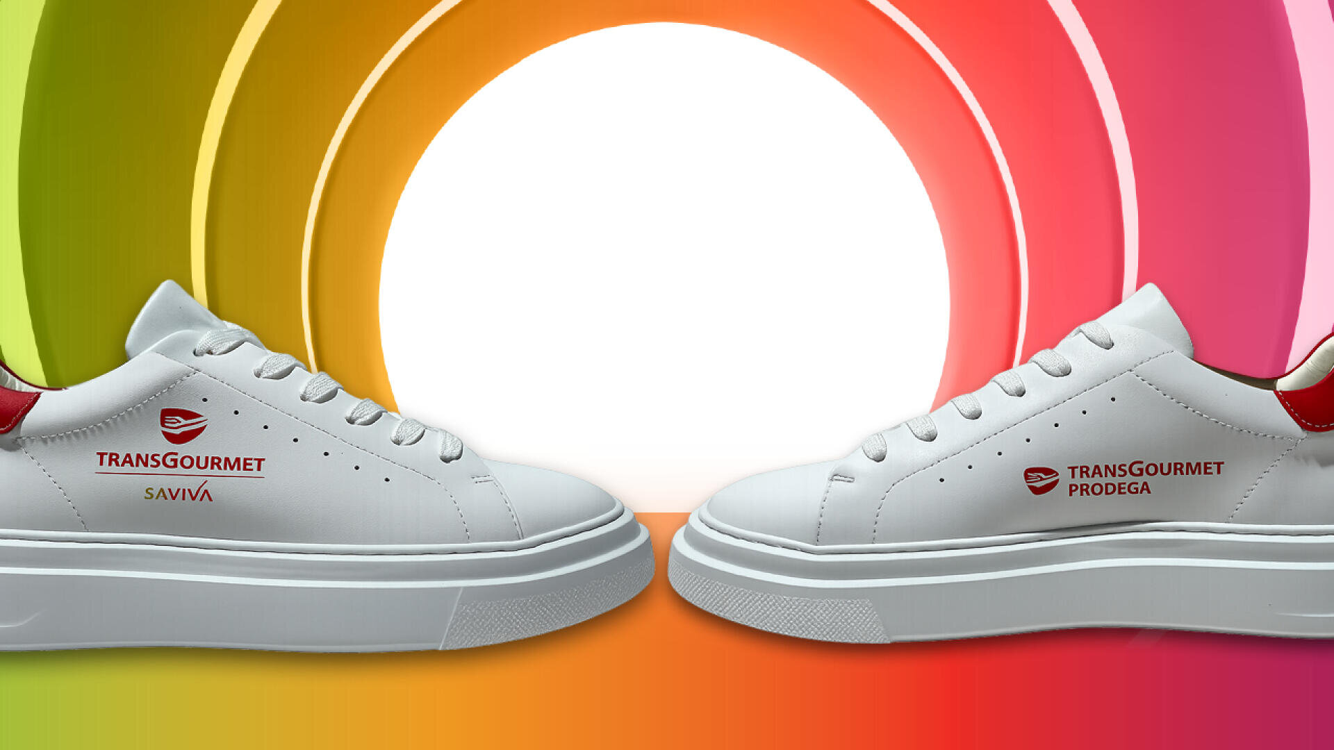 Deux baskets blanches avec des accents rouges, se faisant face et affichant chacune un logo Transgourmet différent, sur un fond lumineux d'arcs concentriques aux couleurs de l'arc-en-ciel, avec un centre d'un blanc éclatant.
