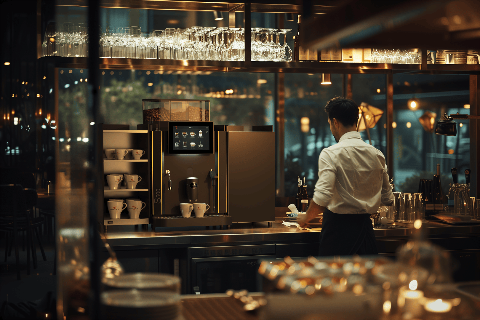 Ein Barista im weißen Hemd steht an einem Tresen in einem modernen, warm beleuchteten Café und bedient eine große Kaffeemaschine mit Touchscreen, umgeben von Tassen und Gläsern.