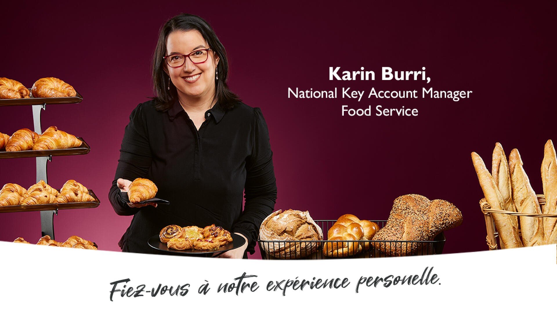 Une femme à lunettes se tient debout, souriante, avec un plateau de pâtisseries assorties. Elle est entourée de croissants, de petits pains et de baguettes. Le texte indique qu'il s'agit de Karin Burri, responsable national des grands comptes, service alimentaire.