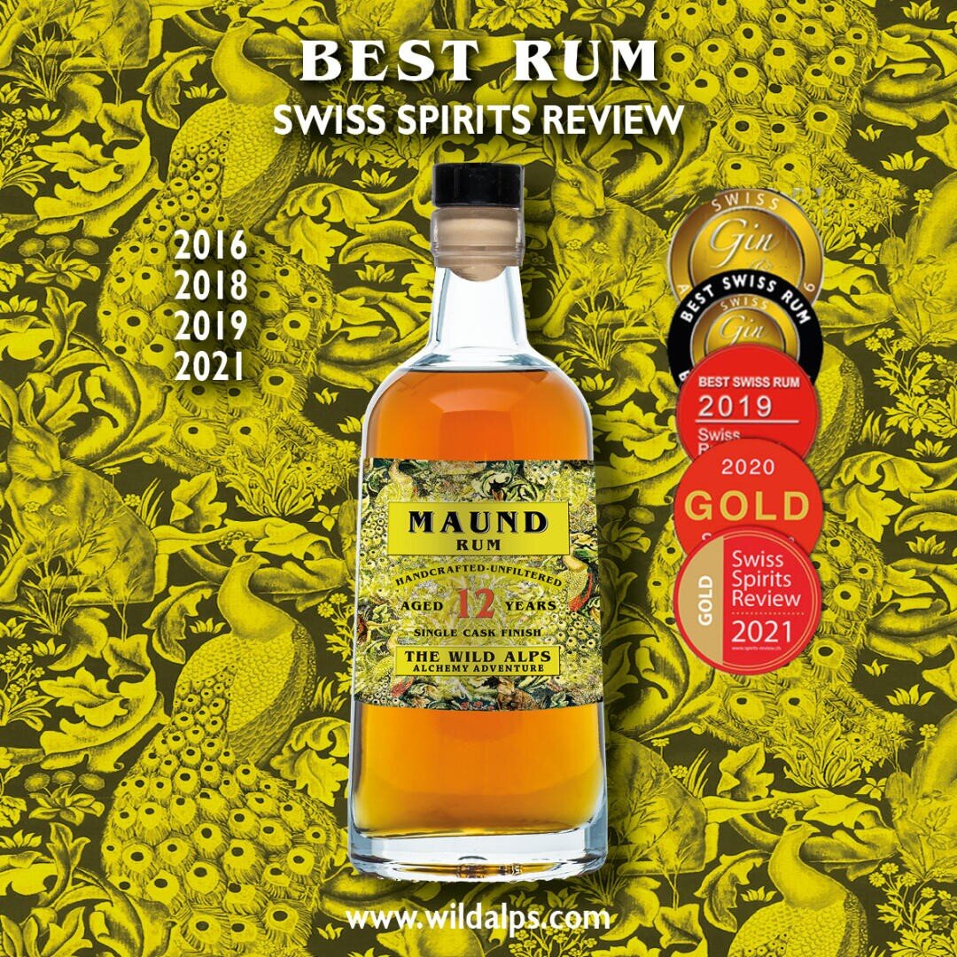 Une bouteille de rhum MAUND est placée au centre sur un fond jaune avec des motifs de fleurs et d'animaux. La bouteille porte une étiquette verte et plusieurs médailles dorées et rouges sont représentées, indiquant des distinctions de 2016 à 2021.