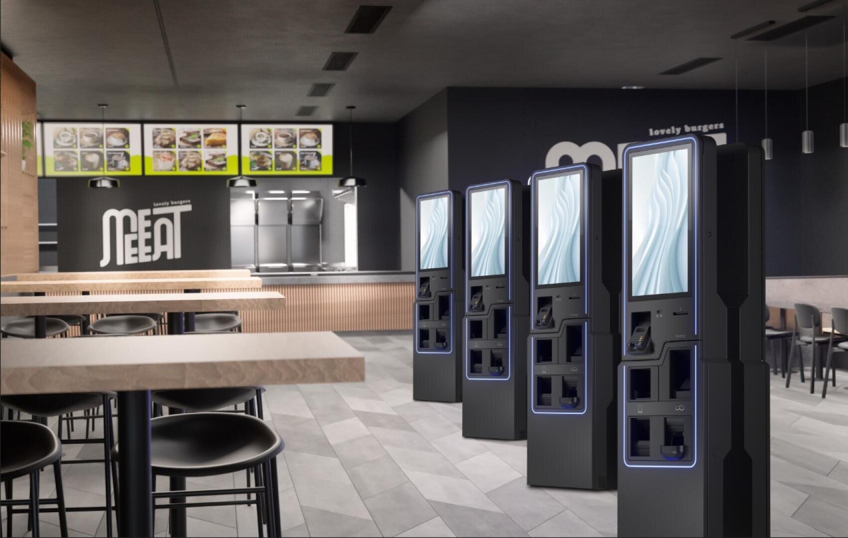 Ein modernes Fast-Food-Restaurant mit mehreren digitalen Selbstbedienungskiosken, Holztischen und -stühlen, Menütafeln an der Wand und einer Theke im Hintergrund mit der Aufschrift MEET.