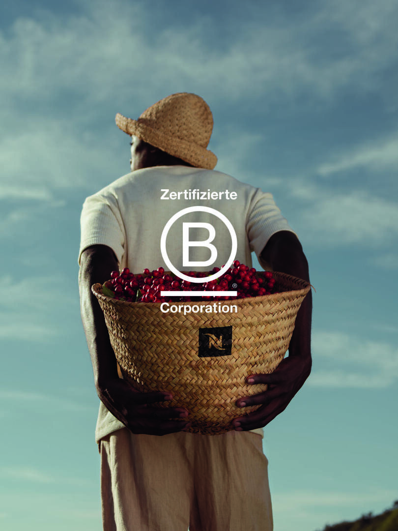 Eine Person mit Strohhut hält einen großen geflochtenen Korb, der mit roten Beeren gefüllt ist, und steht im Freien unter blauem Himmel. Das Logo der "Zertifizierten B Corporation" ist mittig über dem Bild angebracht.