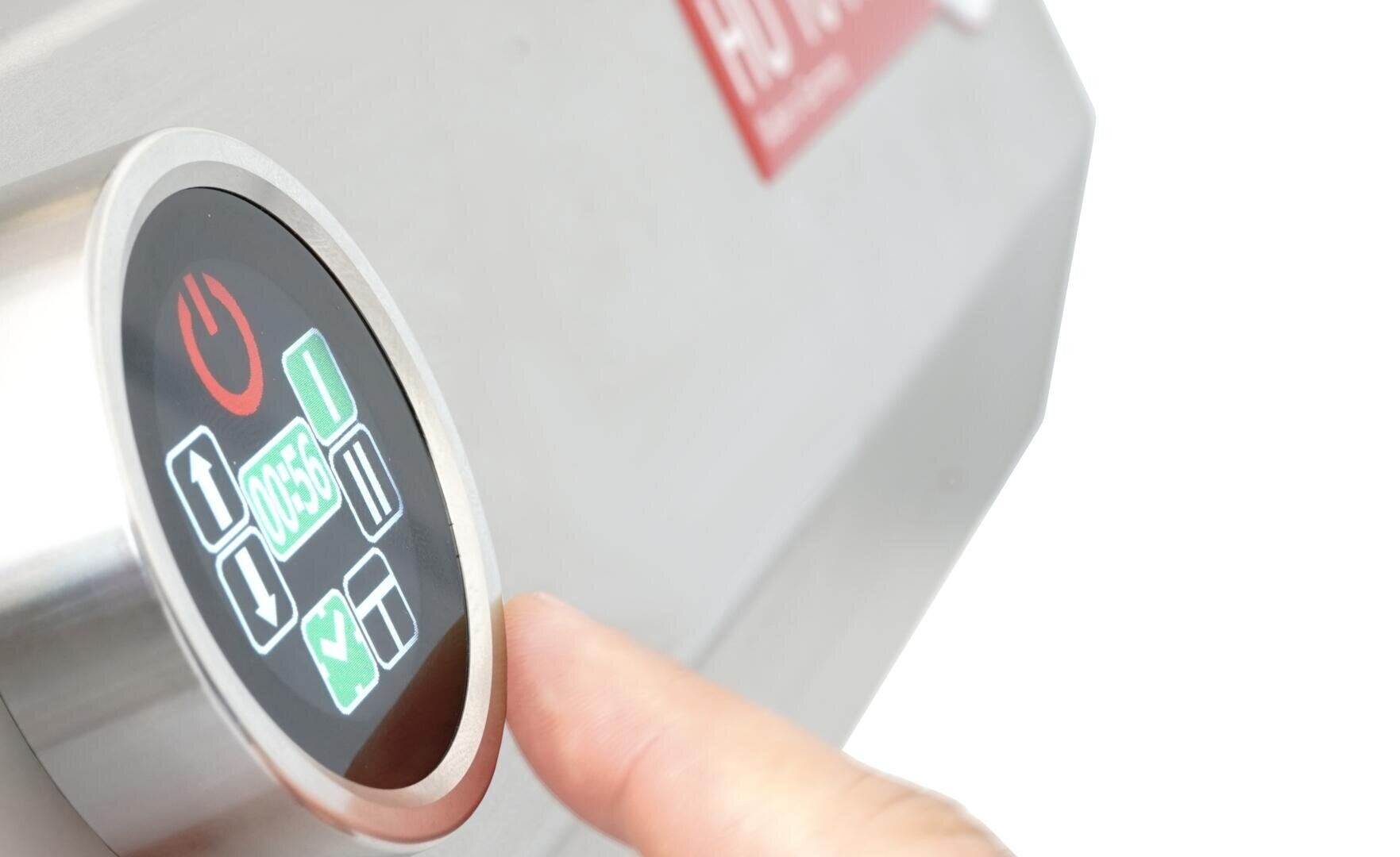 Gros plan d'un doigt appuyant sur un bouton d'un panneau de commande à écran tactile comportant différentes icônes, dont une coche verte et un symbole d'alimentation rouge, sur un appareil métallique.