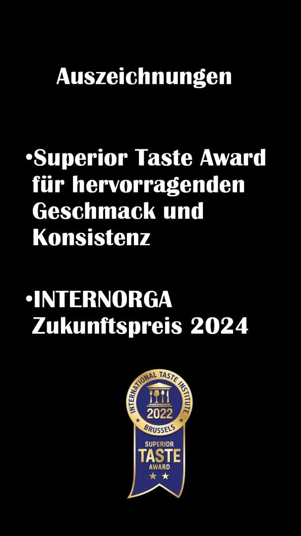 Schwarzer Hintergrund mit weißem deutschen Text, der die Auszeichnungen auflistet: Superior Taste Award für hervorragenden Geschmack und Konsistenz und INTERNORGA Zukunftspreis 2024. Unten ist eine goldene und blaue Superior Taste Award 2022-Plakette abgebildet.