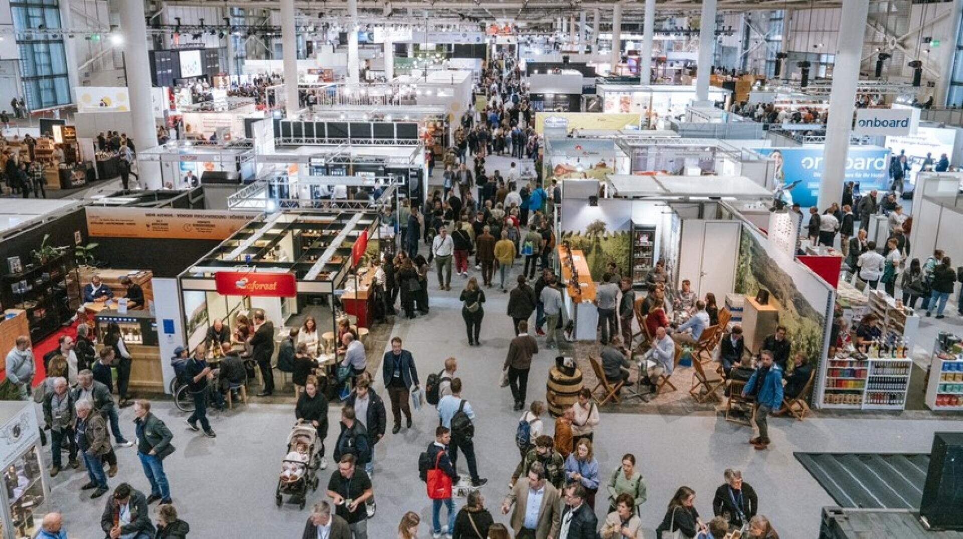 Eine belebte Ausstellungshalle mit zahlreichen Ständen und Auslagen, in denen verschiedene Produkte und Dienstleistungen in einem großen, gut beleuchteten Innenraum präsentiert werden.