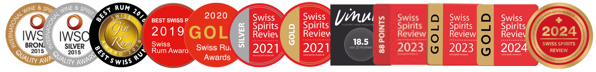 Une série de dix médailles et épinglettes en or, argent, bronze, rouge et noir, chacune portant l'inscription de différentes années et de la Revue Suisse des Spiritueux, représentent les succès remportés lors de concours de spiritueux de 2015 à 2024.