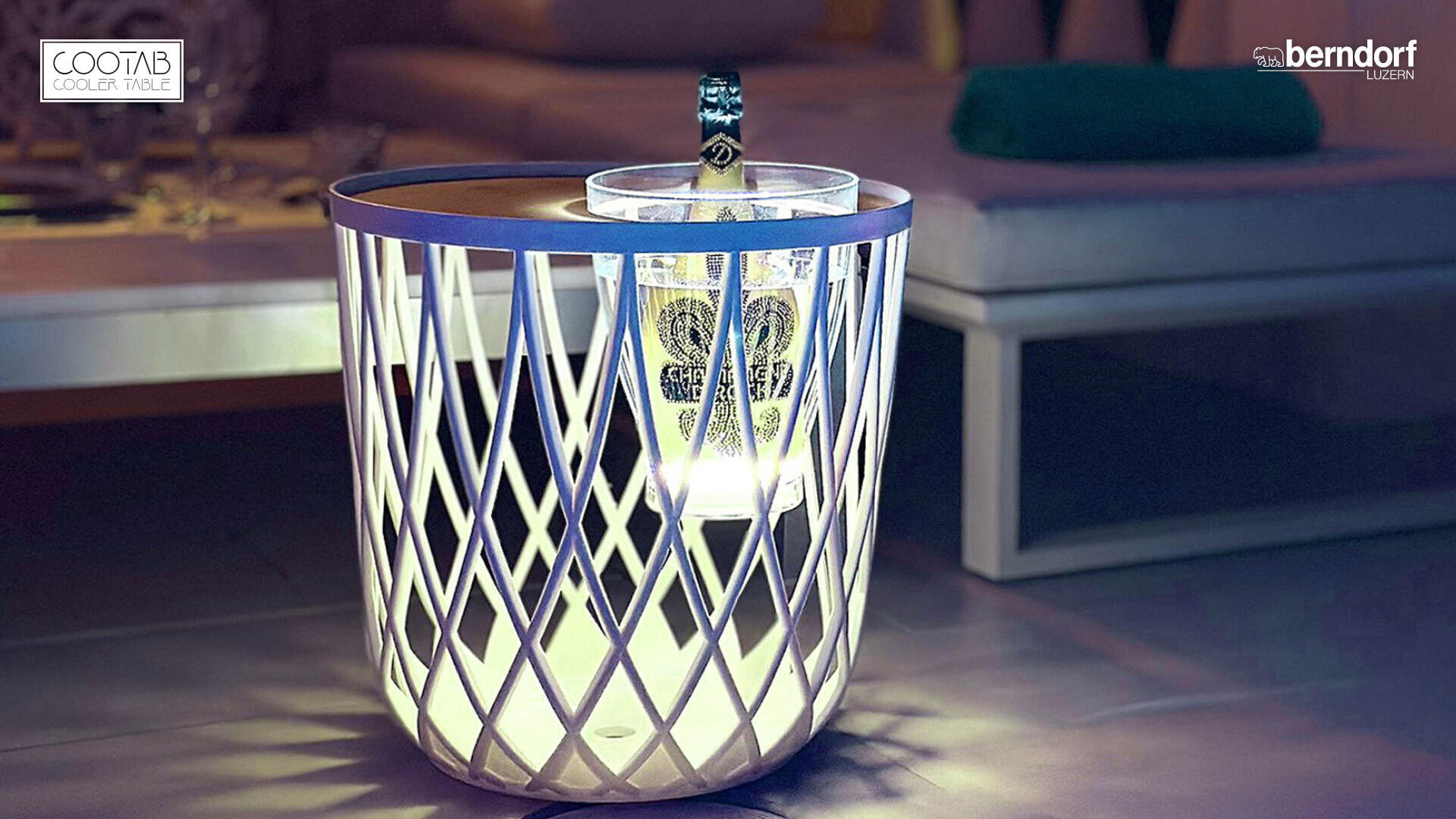 Une table d'appoint moderne et lumineuse, avec un design en treillis, sert également de glacière et contient une bouteille de champagne bien fraîche dans un seau à glace. La scène se déroule dans un salon élégant, avec un canapé en arrière-plan.