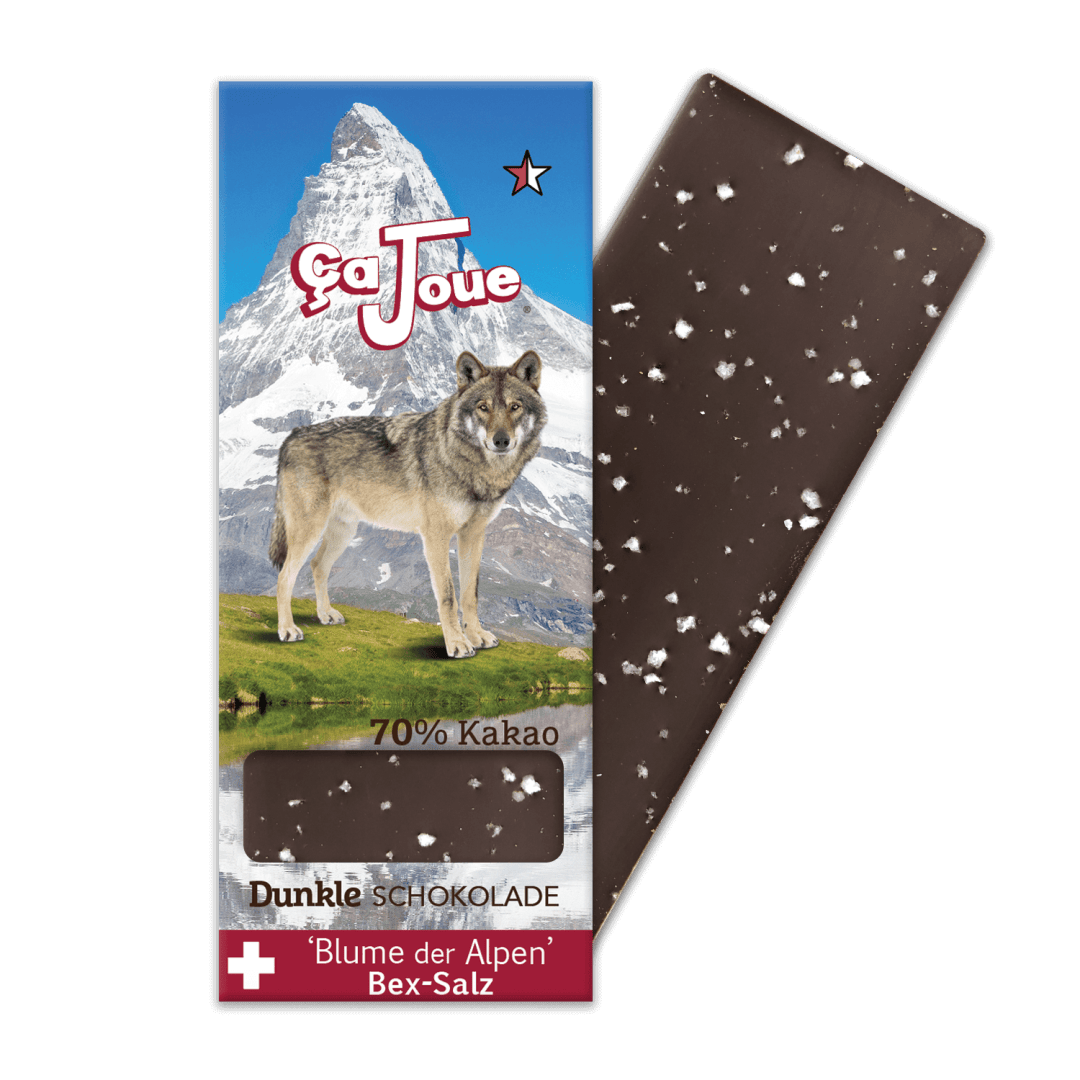 Eine Schokoladentafel mit weißen Flecken wird teilweise von ihrer Verpackung entfernt, auf der ein Wolf, ein verschneiter Berg und Texte wie ÇaJoue, 70% Kakao und Dunkle Schokolade zu sehen sind.