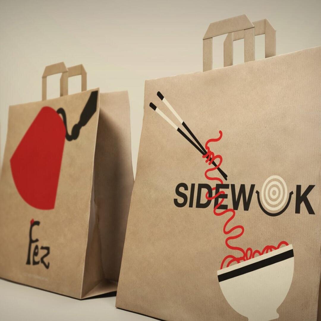 Zwei braune Papiertüten zum Mitnehmen mit kreativen Motiven: Eine zeigt eine rote Teekanne und das Wort Fez, die andere zeigt Stäbchen, die Nudeln über einer Schüssel mit dem Wort SIDEWOK halten.