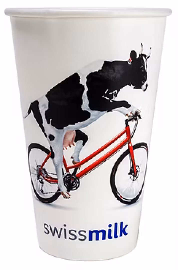 Auf einem weissen Becher ist eine Kuh auf einem roten Fahrrad abgebildet, unten steht der Text swissmilk.