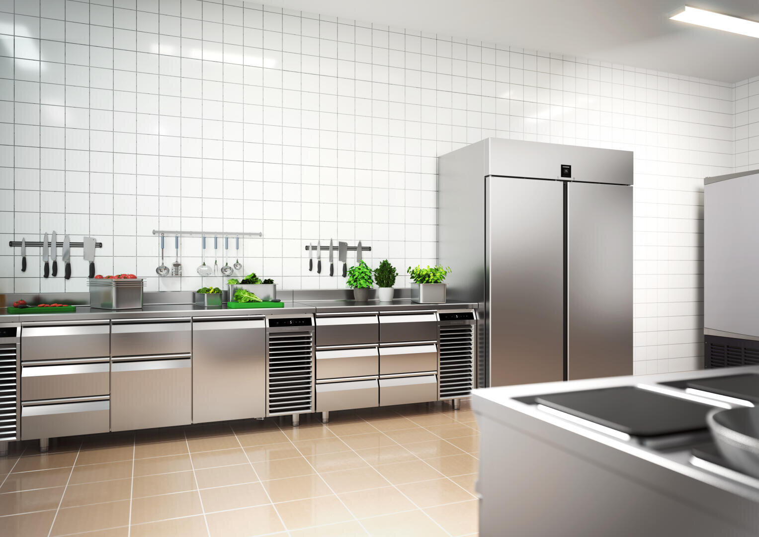 Une grande cuisine moderne avec des comptoirs, des appareils et un grand réfrigérateur en acier inoxydable. Des légumes frais et des herbes aromatiques sont disposés sur le comptoir, les murs sont carrelés en blanc et des ustensiles sont suspendus au-dessus. Le sol est carrelé en marron clair.