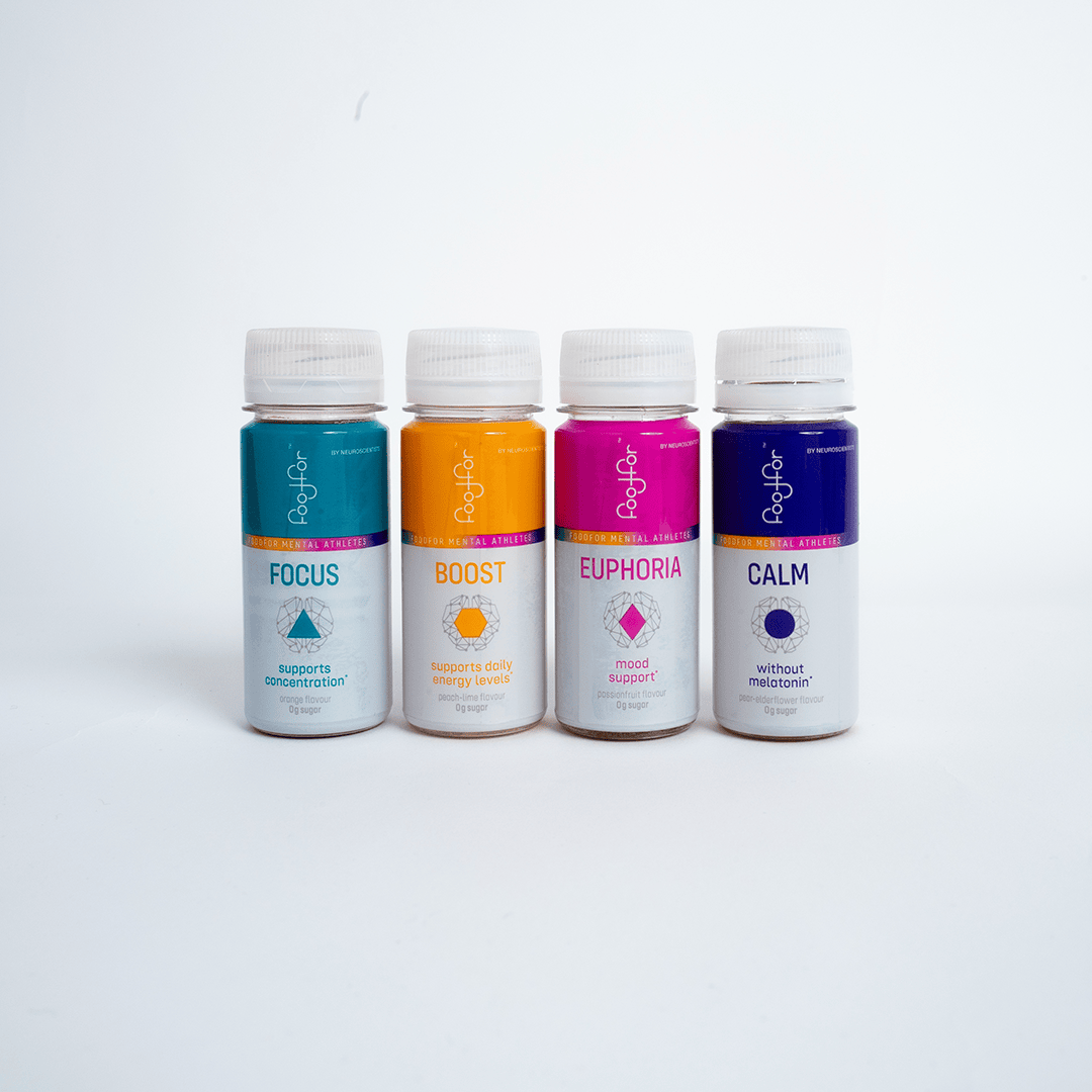 Vier kleine Flaschen mit weißen Verschlüssen sind aufgereiht. Jedes Etikett hat eine andere Farbe und einen anderen Text: Focus (blau), Boost (orange), Euphoria (rosa) und Calm (lila). Die Flaschen stehen auf einem weißen Hintergrund.