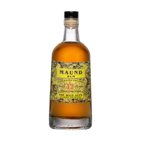 Une bouteille de rhum Maund en verre transparent avec un liquide ambré, portant une étiquette jaune et verte sur laquelle on peut lire MAUND RUM, Aged 12 Years, and The Wild Alps Alchemy Adventure (MAUND RUM, 12 ans d'âge et l'aventure alchimique des Alpes sauvages). La bouteille est munie d'un bouchon noir.
