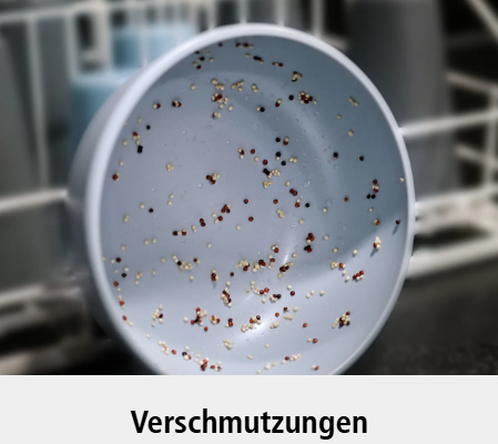 Eine hellblaue Schale mit Essensresten und Flecken im Inneren. Der Hintergrund ist unscharf, und das Wort Verschmutzungen erscheint unter dem Bild.