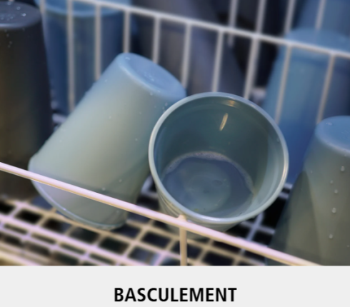 Plusieurs gobelets en plastique sont placés à l'envers et inclinés à l'intérieur d'un panier de lave-vaisselle, des gouttes d'eau étant visibles. Le mot BASCULEMENT est écrit en bas de l'image.