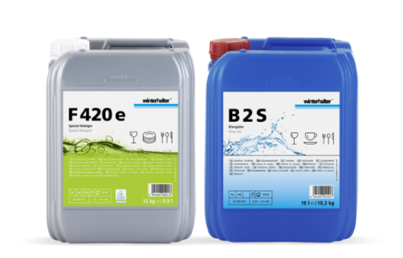 Deux récipients en plastique étiquetés contenant des produits chimiques de nettoyage, un gris avec une étiquette verte portant l'inscription F420e et un bleu avec une étiquette bleue portant l'inscription B2S, tous deux avec des symboles d'ustensiles de cuisine et la marque Winterhalter.