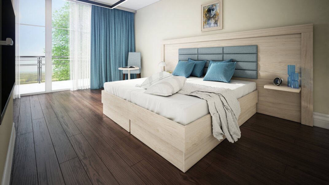 Ein modernes Schlafzimmer mit Holzboden, einem großen Bett mit blau-weißer Bettwäsche, blauen Vorhängen, einem Beistelltisch mit Lampe und einem Schreibtisch in der Nähe eines Fensters mit Blick ins Grüne. Über dem Bett hängt ein gerahmtes Bild.